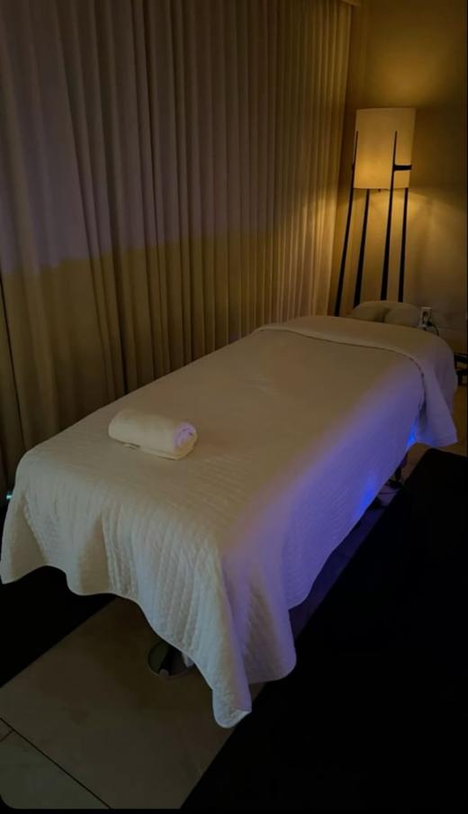 Treatment room with a massage table, soft lamp light, and curtains